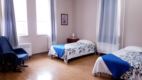 Habitación con 2 camas y una silla. en MHotel Domaine l'Envolée- Maison Fleurie, en Victoriaville