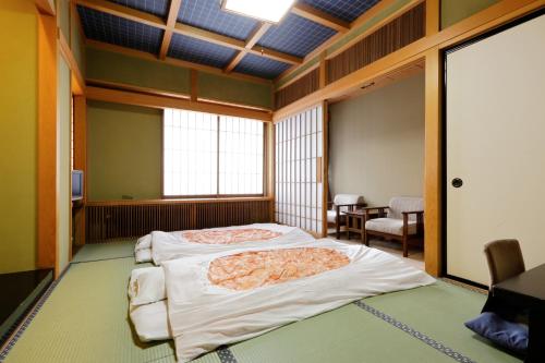 1 dormitorio con 2 camas, mesa y sillas en Okada Ryokan Warakutei, en Takayama