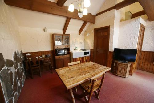 a living room with a wooden table and a kitchen at Minami Aso Luna Observatory Auberge Mori no Atelier in Minami Aso