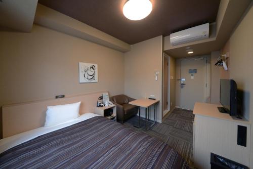 上田市にあるホテルルートイングランド上田駅前のベッドとテレビが備わるホテルルームです。