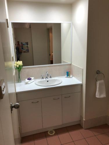 a bathroom with a sink and a large mirror at Beaches Serviced Apartments in Nelson Bay