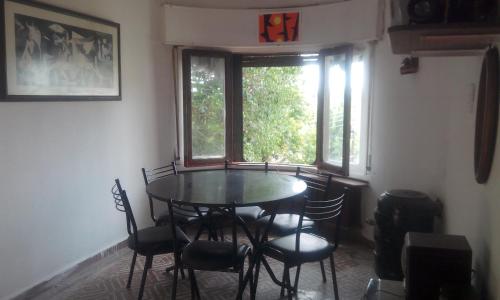 comedor con mesa, sillas y ventana en Habitación en Casa Las Dos Nenas en Río Ceballos