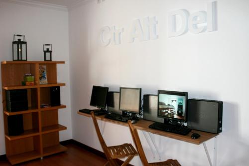 a group of four computer monitors on a desk at Hostel 2300 Thomar in Tomar