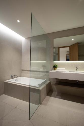 a bathroom with a tub and a sink and a mirror at Ariama Serviced Residence in Jakarta