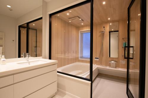 Un baño con bañera, lavabo y ducha. en Yotei Yama House, en Kutchan