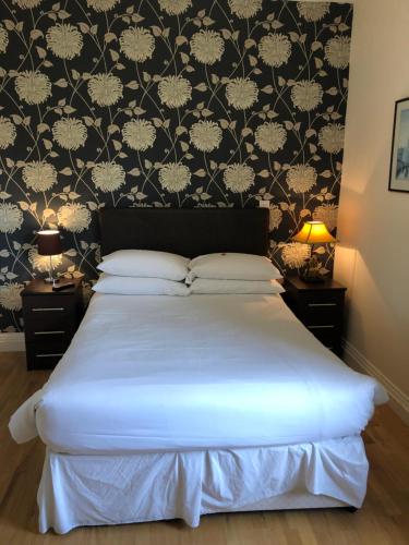 a bedroom with a bed with a black and white wallpaper at Homerton House Apartments in Cambridge