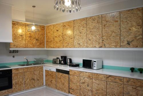a kitchen with wooden cabinets and a microwave at Hostel 2300 Thomar in Tomar
