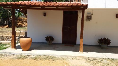 a porch with a door and a vase in front at Emma's Sea View in Hiriketiya