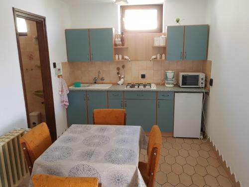 "ハルカーニャ"にあるÁgnes Apartmanokのキッチン(青いキャビネット、テーブル、椅子付)