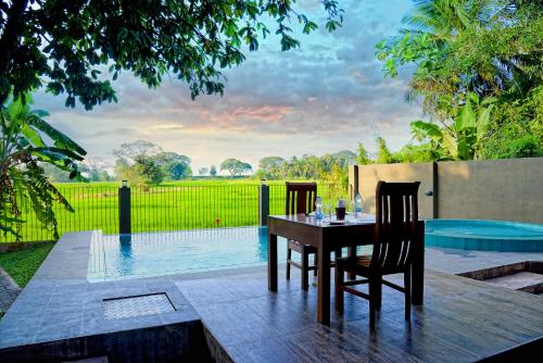 a table and chairs on a patio with a swimming pool at Green View Resort - Anuradhapura in Anuradhapura
