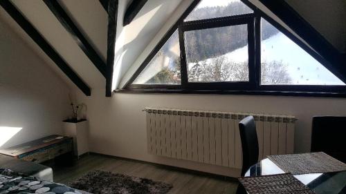 a attic room with a large window and a radiator at Treasure Mountain Predeal in Predeal