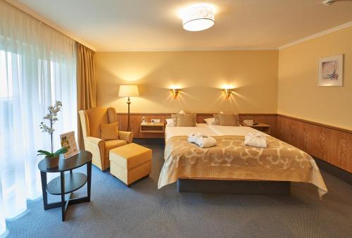 een hotelkamer met een bed en een stoel bij Landhotel Kallbach - 4 Sterne SUPERIOR in Hürtgenwald