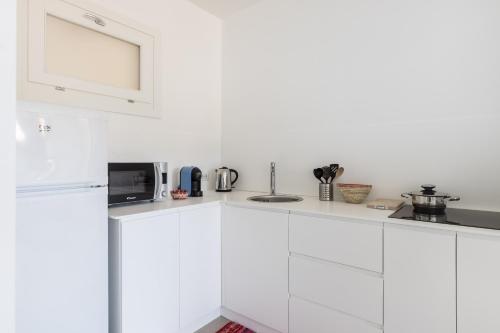 a white kitchen with white cabinets and a microwave at Appartamenti Shardana in Villasimius