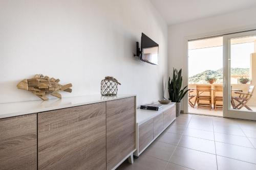 a kitchen with white walls and wooden cabinets at Appartamenti Shardana in Villasimius