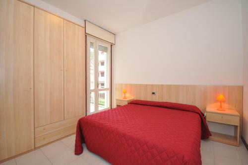 a bedroom with a red bed and a window at Condominio Delfino in Bibione