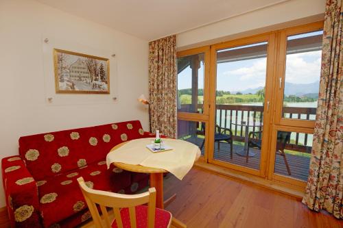 a living room with a couch and a table and a balcony at Appartement-Hotel Seespitz in Füssen