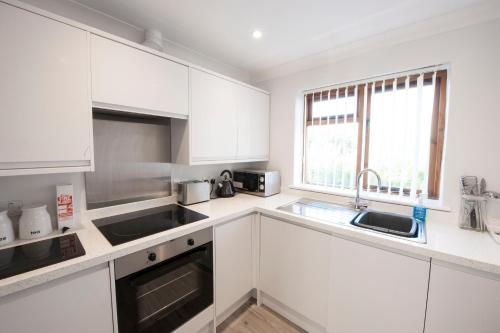 a white kitchen with white cabinets and a sink at High Hedges Apartment B in Oxford