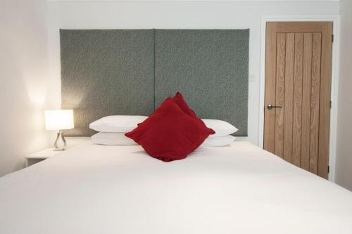 ein rotes Kissen auf einem weißen Bett in der Unterkunft High Hedges Apartment B in Oxford