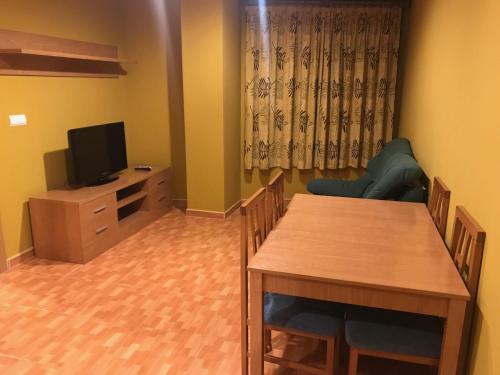 a living room with a dining table and a television at Apartamentos Duquesa Sierra Nevada in Pinos Genil