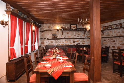 a dining room with a long table in a restaurant at Djudjeva Kyshta Hotel in Panagyurishte