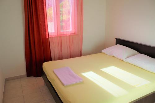 a small bedroom with a bed with a window at Apartmani Marija in Duće