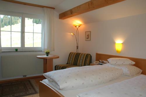 a bedroom with a bed and a chair and a window at Haus Anja in Lech am Arlberg