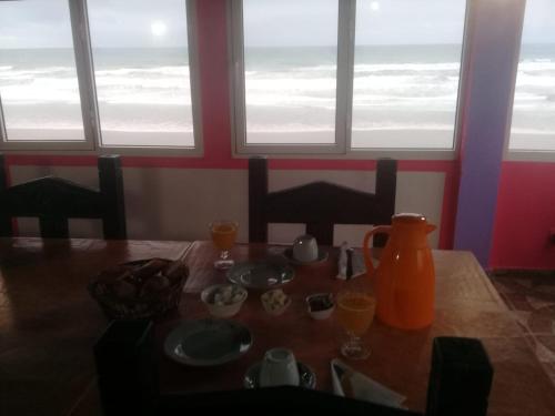een eettafel met uitzicht op de oceaan bij Hôtel La Corniche in Akhfennirr