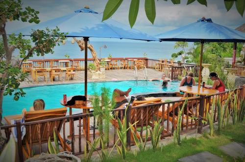 a group of people sitting around a swimming pool at Ocean Terrace Suite And Spa Luxury in Nusa Penida