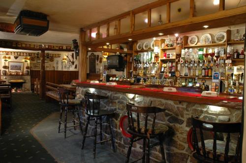 a bar with stools in a room with a lot of alcohol at Exmoor White Horse Inn in Exford