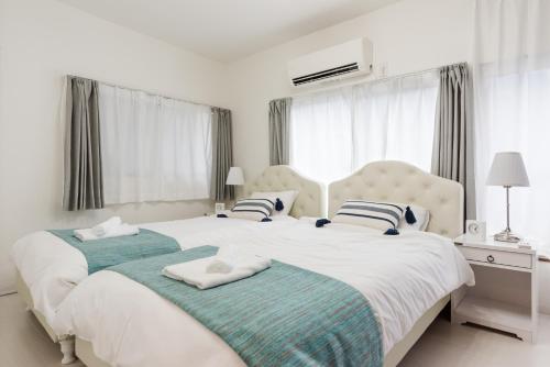 a white bedroom with two beds and a window at Gracias Arakawa - Great Access to UENO & ASAKUSA area in Tokyo
