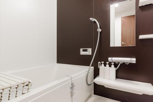 uma casa de banho com uma banheira branca e um espelho. em Gracias Arakawa - Great Access to UENO & ASAKUSA area em Tóquio