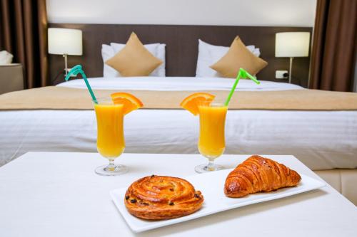 una mesa con dos vasos de zumo de naranja y cruasanes en My Hotel Yerevan, en Ereván