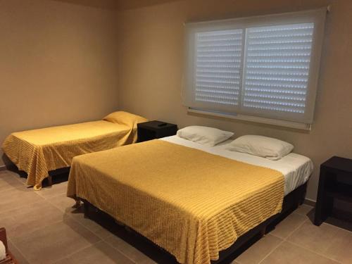 a bedroom with two beds and a window with blinds at Aires de Río in Bella Vista