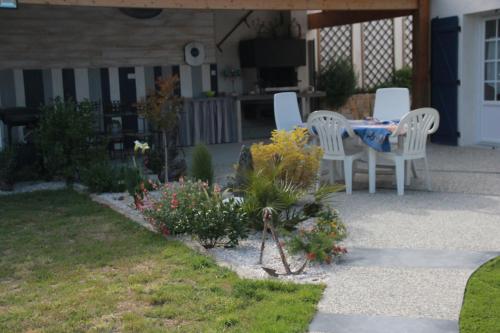 - une terrasse avec une table, des chaises et des fleurs dans l'établissement KARABI, à Barbâtre