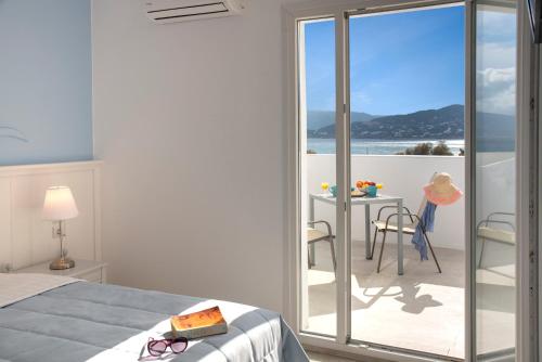 a bedroom with a bed and a balcony with a table at Naiades Marina Hotel in Agios Nikolaos