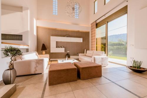 een woonkamer met witte meubels en een groot raam bij Filerimos Oasis Luxury Villa in Ialyssos