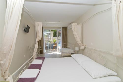 uma cama branca num quarto com uma janela em Villa Bougenvilia Tomas em Tučepi
