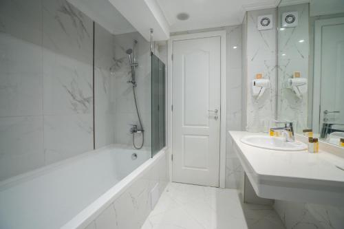 een witte badkamer met een bad en een wastafel bij Perla Royal Hotel - All Inclusive in Primorsko