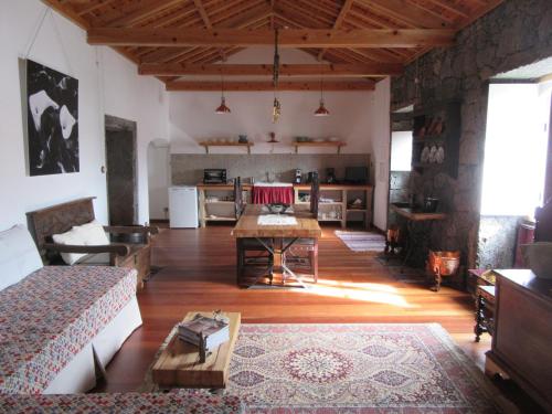 a living room with a table and a kitchen at O Antigo Lagar in Cinco Ribeiras