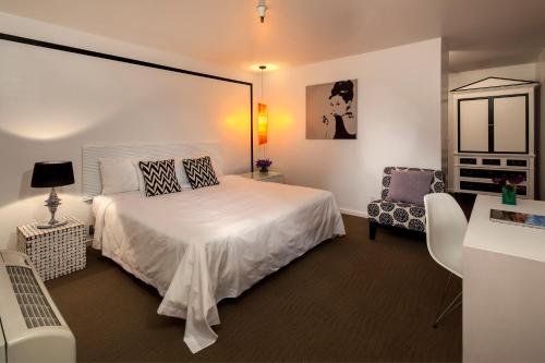 a bedroom with a white bed and a chair at Aqua Soleil Hotel and Mineral Water Spa in Desert Hot Springs