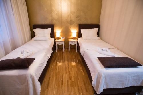two twin beds in a room with two tables at Apartment Exclusive and Studio in Subotica