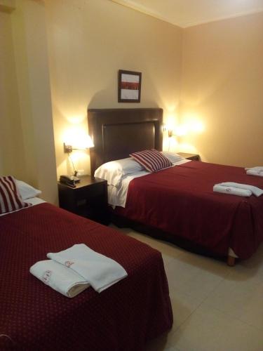 a hotel room with two beds with red sheets at Hotel Le Park in San Miguel de Tucumán