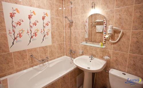 y baño con lavabo, bañera y aseo. en Luna Hotel, en Chişinău