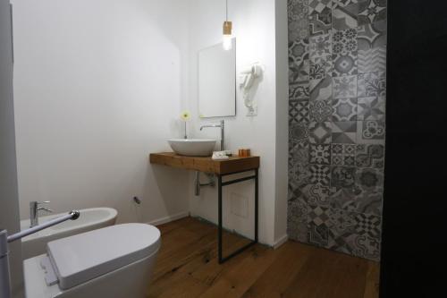 a bathroom with a white toilet and a sink at Reusuite in Ragusa