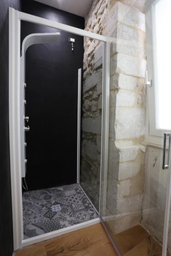 a shower with a glass door next to a stone wall at Reusuite in Ragusa