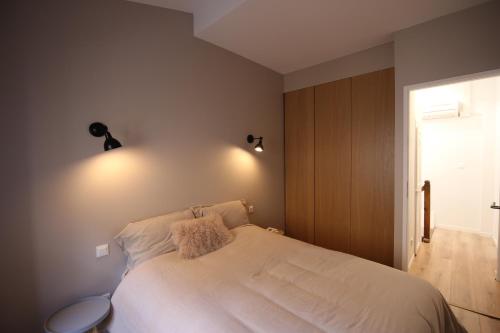 Maison petite côte في قرقشونة: غرفة نوم مع سرير مع مصباحين على الحائط