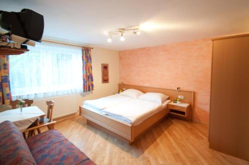 ein Schlafzimmer mit einem Bett, einem Fenster und einem Sofa in der Unterkunft Haus Fritzenwallner Appartement 2 in Wagrain