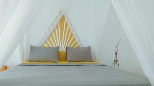 a bed with two pillows in a room at Café des Arts Gili Air in Gili Islands