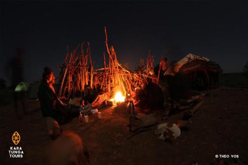 a group of people sitting around a fire at night at Kara-Tunga Safari Camp in Moroto
