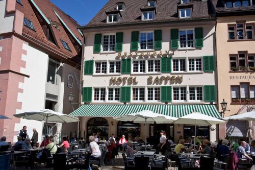a group of people sitting at tables in front of a building at Hotel Rappen am Münsterplatz in Freiburg im Breisgau